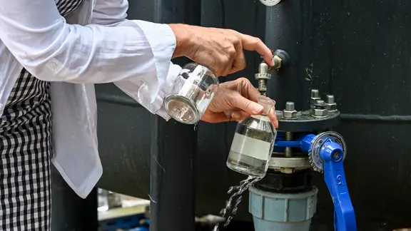 Ein Frau füllt Grundwasser in eine Flasche ab