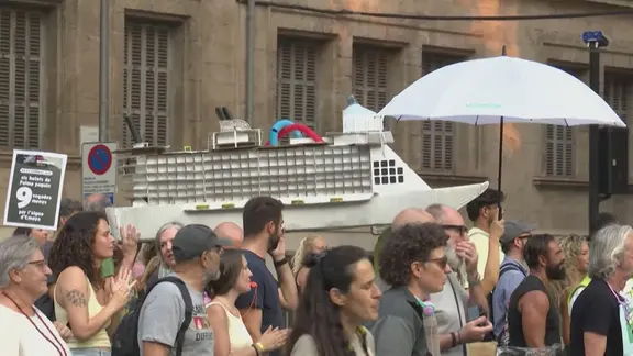Protestierende, tragen Kreuzfahrtschiff aus Pappe
