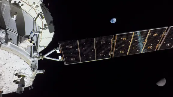 Das Raumschiff Orion, noch ohne Besatzung während der Artemis I Mission. Hinter dem Solarsegel sind Mond und Erde zu erkennen.