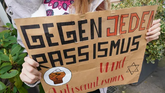 Ein Plakat mit der Aufschrift „Gegen jeden Rassismus und Anitsemitismus“ hält eine Teilnehmerin bei der Demonstration vom Bündnis „#unteilbar Sachsen-Anhalt - Für eine demokratische und offene Gesellschaft – Solidarität statt Ausgrenzung!“.