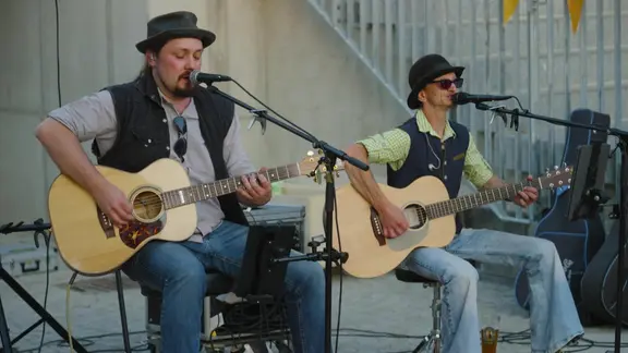 Zwei Männer spielen sitzend Gitarren