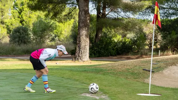 Eine Footgolf-Spielerin schießt einen Ball Richtung Loch