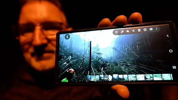 Ein Mann zeigt ein Handy mit einem Bild darauf. Nachtbild