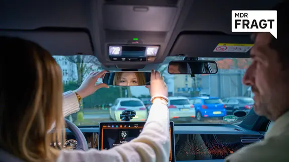 Fahrschülerin richtet sich im Fahrschulwagen den Rückspiegel ein