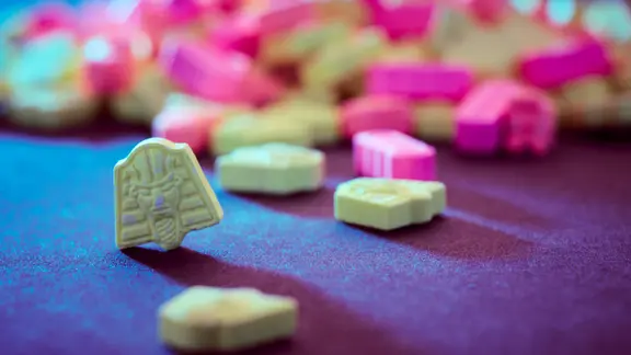 Bunte Tabletten liegen auf einem Tisch. 
