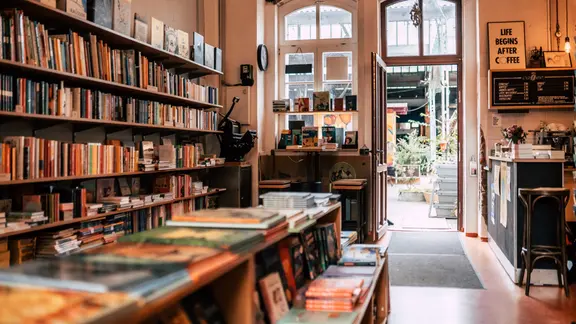 Blick in einen buchladen mit vollen Regalen und großen Fenstern.