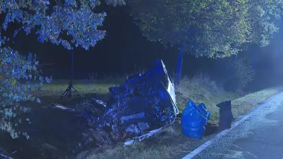 Ein offenbar nacch einem Unfall zerstörtes Auto im Straßengraben in der Nacht.