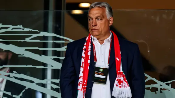 Viktor Orbán, mit ungarischem Fanschal um den Hals, schaut unzufrieden bei einem Fußballspiel.