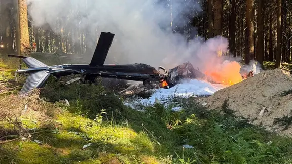 Ein Hubschrauber brennt an der Absturzstelle im Erzgebirge.