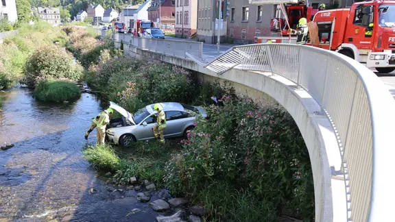 Rettungkräfte kümmern sich um ein Auto, das in einen Fluss gefahren ist. 