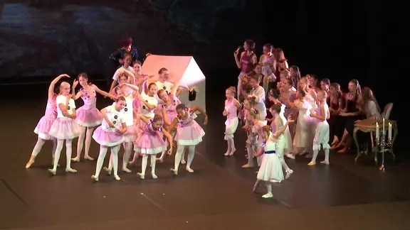 Das Bild zeigt tanzende Kinder auf der Theaterbühne.