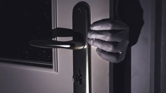 Eine behandschuhte Hand an einer Tür
