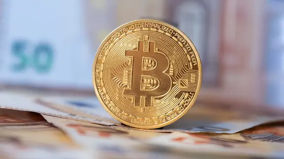 Bitcoin-Münze mit Euro-Geldscheinen