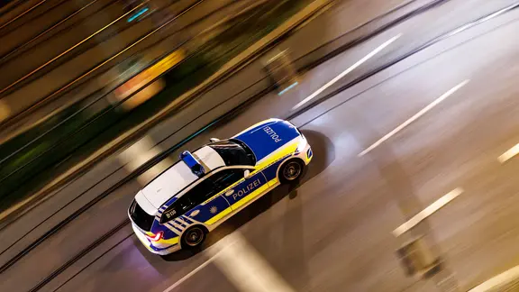 Ein Einsatzfahrzeug der Polizei ist nachts auf einer Straße unterwegs.