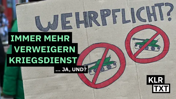 Demonstrant hält Anti-Wehrpflicht-Transparent mit durchgestrichenen Panzern.