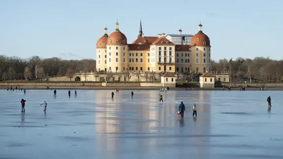 Schlittschuhläufer auf dem Schlossteich vor dem Schloss Moritzburg.
