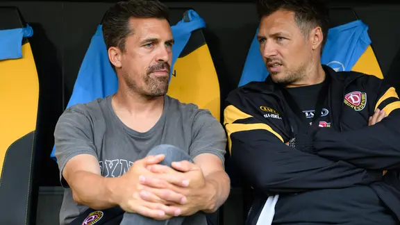 Trainer Thomas Stamm (Dynamo Dresden, l) und Sören Gonther, Dynamos Sportdirektor, sitzen auf der Bank.