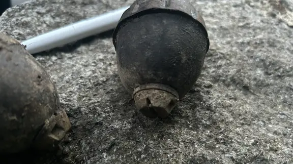 Zwei rostige Granaten liegen auf dem Boden.