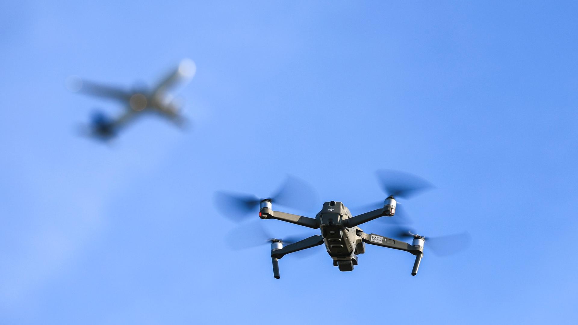 Eine Drohne fliegt vor einem startenden Flugzeug | picture alliance/dpa | Jan Woitas