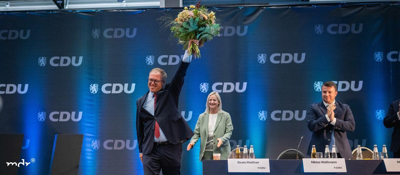 Mario Voigt (CDU, l), Ministerpräsident von Thüringen, winkt nach seiner Wiederwahl zum Landesvorsitzenden der CDU Thüringen mit einem Blumenstrauß
