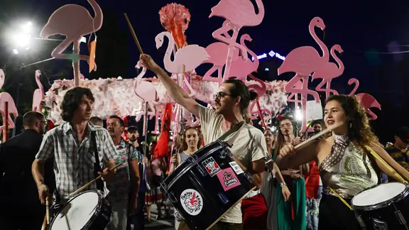 Menschengruppe mit Trommeln und Schaumstoff-Flamingos auf einer Demonstration