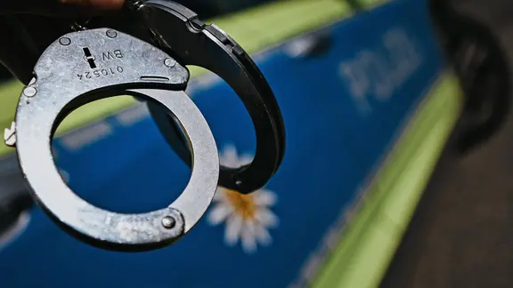 Handschellen und Polizeifahrzeug