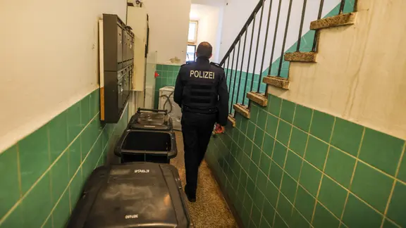 Ein Polizeibeamter geht durch ein Treppenhaus bei einer Kontrolle gegen kriminelle Geschäftsmodelle mit Schrottimmobilien und Sozialbetrug.