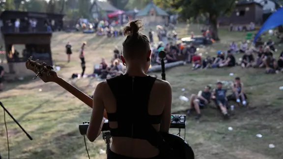Eine Musikerin mit Gitarre von hinten Fotografiert auf der Bühne