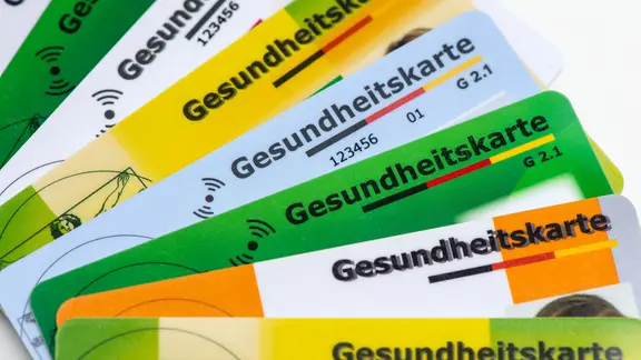 Verschiedene Gesundheitskarten von Krankenversicherungen liegen zusammen.