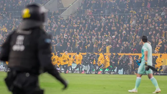 Einsatzkräfte sichern das Spielfeld bei der Partie Dynamo Dresden gegen Hertha BSC und drängen Fans zurück in den K-Block.