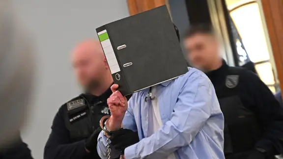 Der Angeklagte wird von Justizbeamten in den Sitzungssaal im Landgericht in Leipzig geführt. 