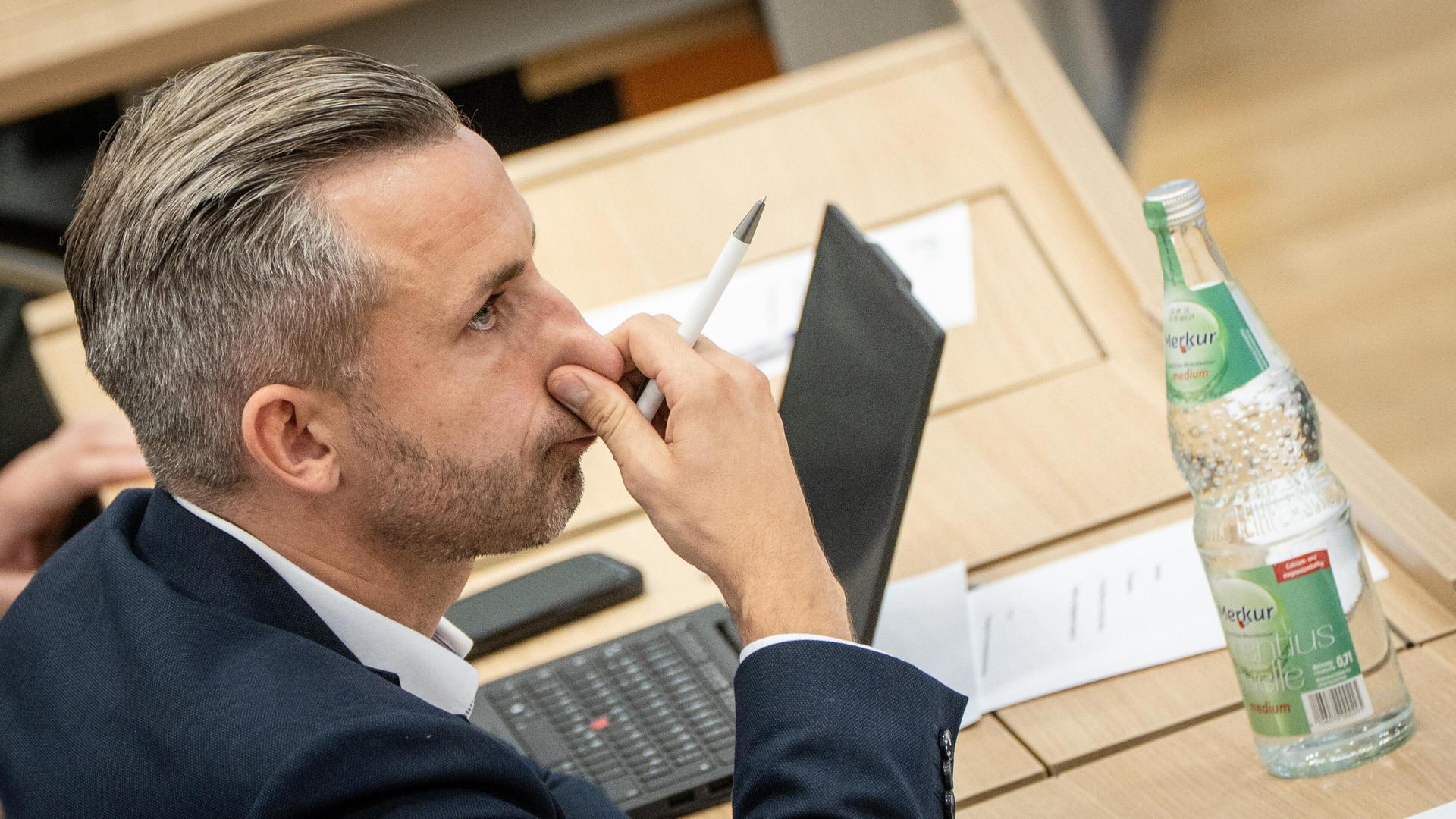 Ulrich Siegmund, AfD-Abgeordneter, während der Debatte im Landtag, greift sich an die Nase. Auf dem Tisch vor ihm steht eine Flasche. | picture alliance / Chris Emil Janßen | chris.emil-janssen.de