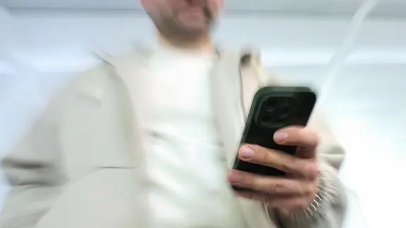 Symbolbild Telefonbetrug: Ein Mann mit einem Smartphone