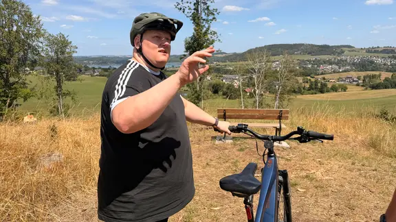 Ein Radfahrer steht mit seinem Rad an einem Aussichtspunkt