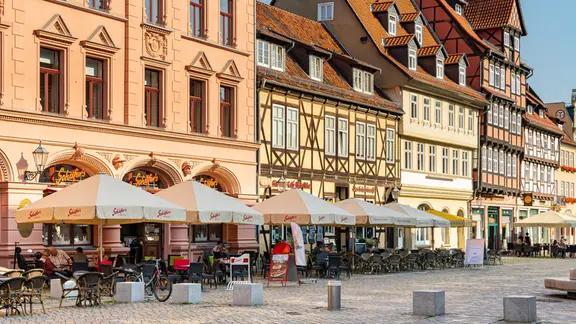 Auf dem Marktplatz in Quedlinburg stehen mehrere Stühle und Tische der Außengastronomie. 