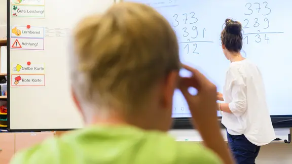 Ein Lehrerin schreibt eine Mathematikaufgabe auf eine digitale Schultafel im Klassenraum einer 4. Klasse einer Grundschule in der Region Hannover. 