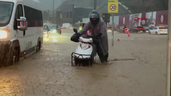 Eine Straße in Istanbul ist überflutet. Neben einem Transporter schiebt ein Mann seinen Motorroller, das Wasser steht knietief auf der Straße.