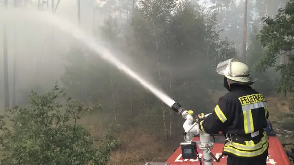 Ein Feuerwehrmann löscht einen Waldbrand. 