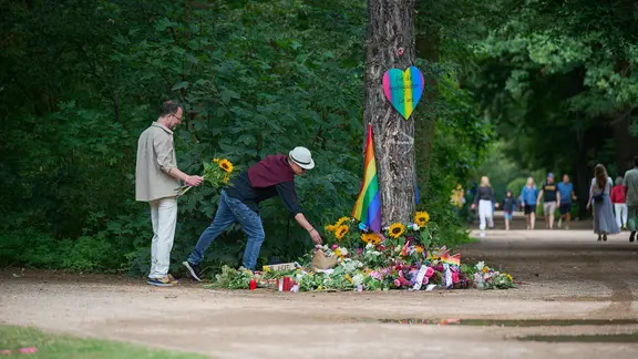 Menschen trauern und legen Blumen und Beileidsbekundungen an einen der Tatorte im Berliner Tiergarten, zwei Tage nach dem Anschlag auf die Feiern des 48. Berliner Christopher Street Day (CSD) mit einer Toten und 29 teils schwer Verletzten.