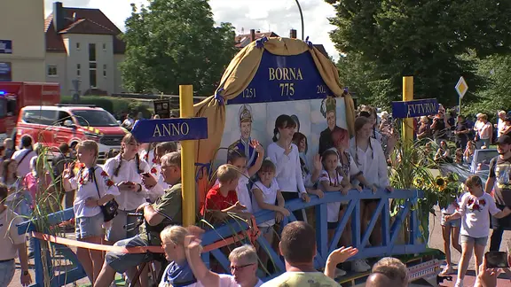 Kinder winken bei Festumzug von einem Wagen