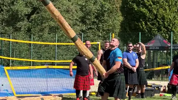 Ein Mann stemmt einen großen Baumstamm nach oben. 