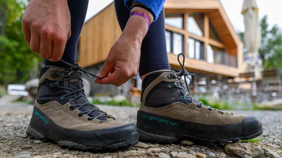 Eine Frau schnürt ihre Wanderschuhe vor dem Naturhotel „Basislager Fichtelberg“.