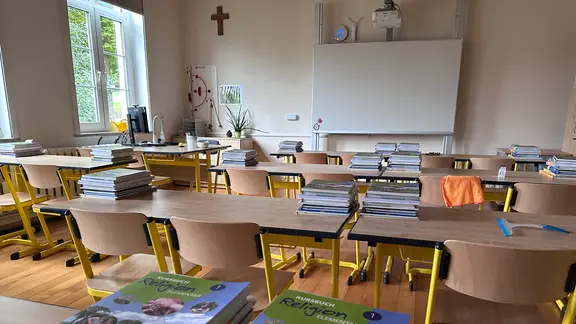 In einem Klassenzimmer liegen Unterrichtsmaterialien auf den Tischen bereit. 