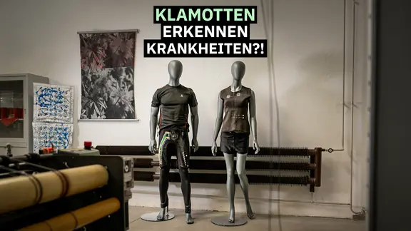 Zwei Kleiderpuppen tragen futuristisch anmutende Kleidung, dazu der Schriftzug: "Klamotten erkennen Krankheiten?!" 