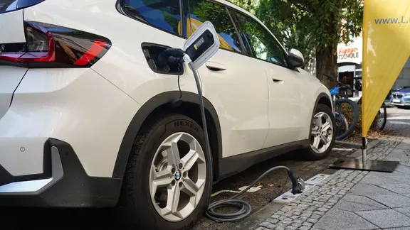 Ein E-Auto wird an einem Bordstein geladen. 