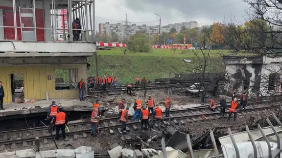 Eine oberirdische U-Bahnstation in der ukrainischen Hauptstadt Kiew ist bei einem russischen Luftangriff beschädigt worden. Einsatzkräfte räumen auf und reparieren die Gleise. 