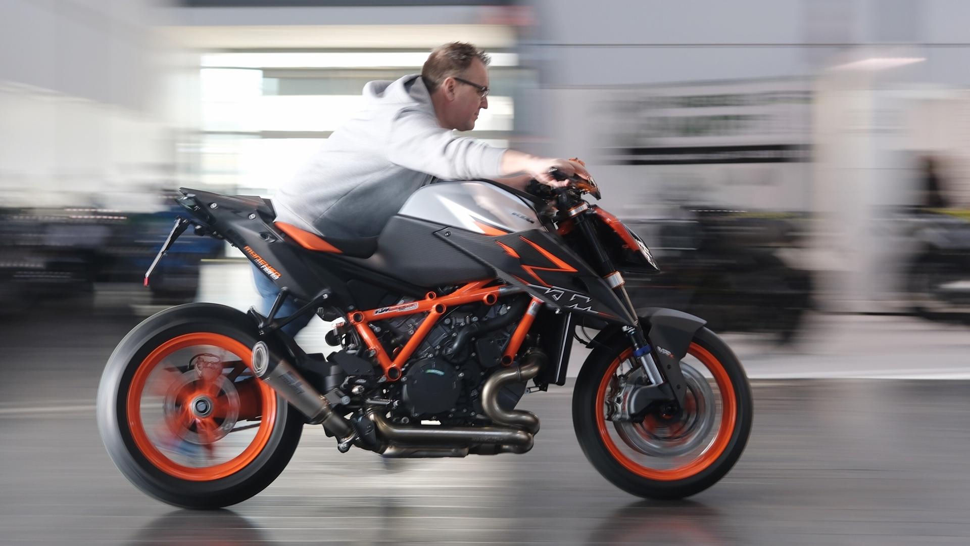 Ein Mann schiebt auf einer Motorradmesse eine Maschine vom Typ KTM Super Duke 1290 R Evo.  | picture alliance/dpa | Sebastian Willnow