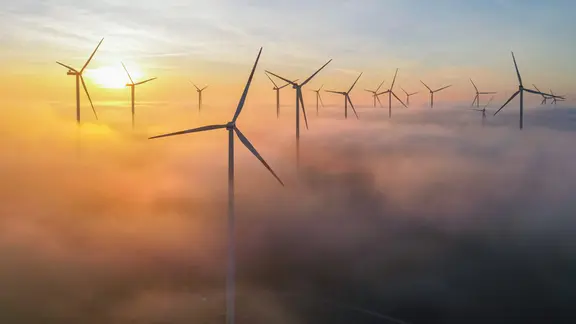 Die Morgensonne leuchtet über dem Nebel zwischen Windenergieanlagen im östlichen Brandenburg 