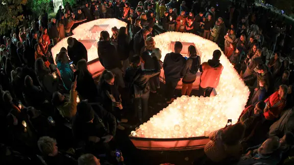 Besucher des Lichtfestes stelltenihre Kerzen in die große 89 in der Leipziger Innenstadt.
