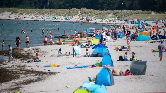 Menschen am Strand des Seebads. Viele Ostseebäder machen derzeit mit Aushängen auf die Gefahr durch Vibrionen aufmerksam. 